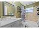 Bathroom featuring a shower-tub combo, vanity, and a black framed mirror with green painted walls at 11114 Freedom Way, Seminole, FL 33772