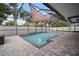 Inviting screened pool with sunshade, stone patio, tropical landscaping, and fenced backyard at 11310 Callaway Pond Dr, Riverview, FL 33579