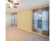 Carpeted bedroom featuring light-colored walls, ceiling fan, and dual windows with patterned curtains at 12523 Longstone Ct, New Port Richey, FL 34655