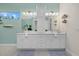 Well-lit bathroom with double sinks, white cabinetry, and neutral tile flooring at 15909 39Th E Gln, Parrish, FL 34219