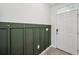 Foyer featuring a green paneled accent wall with coat hooks, a white front door, and tile flooring at 16051 Soft Fern Trce, Odessa, FL 33556