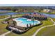 Aerial view of the community pool with sunbathing area, lush landscaping, and lake at 16614 Mosaic Oar Dr, Wimauma, FL 33598