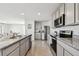 Well-lit kitchen featuring stainless steel appliances, granite countertops, gray cabinets and tile flooring at 16614 Mosaic Oar Dr, Wimauma, FL 33598
