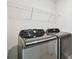 Modern laundry room featuring new Samsung washer and dryer units and a wire shelf for storage at 16614 Mosaic Oar Dr, Wimauma, FL 33598