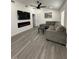 Bright living room featuring gray wood flooring, a fireplace, ceiling fan, and a gray sectional sofa at 1913 Park Ave, Tarpon Springs, FL 34689