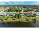 Aerial view showcasing a home with a screened pool and a wooden dock on a tranquil pond in a residential neighborhood at 3381 Conway Blvd, Port Charlotte, FL 33952