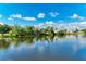 A tranquil pond with lush shoreline vegetation reflecting the clear blue sky and puffy white clouds at 3381 Conway Blvd, Port Charlotte, FL 33952