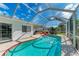 A refreshing screened-in pool with an intricate tile border, complemented by a seating area and lush landscaping at 3381 Conway Blvd, Port Charlotte, FL 33952