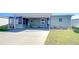 Charming home exterior with a well-maintained lawn, covered carport, and a welcoming screened porch at 37530 Corey Lewis Ave, Zephyrhills, FL 33541