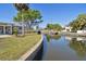 Scenic canal-front home with lush landscaping, a concrete seawall and dock under a clear blue sky at 5167 Venetian Ne Blvd, St Petersburg, FL 33703