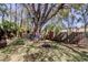 Landscaped backyard with mature trees, wooden fence, and swing set providing an outdoor play area at 592 Deer W Run, Palm Harbor, FL 34684