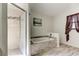 Bright bathroom featuring a tiled tub, a walk-in shower with glass door, a window, and neutral wall art at 592 Deer W Run, Palm Harbor, FL 34684