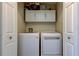 This laundry room has a modern washer, dryer, and overhead storage at 592 Deer W Run, Palm Harbor, FL 34684