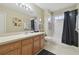 Bright bathroom featuring a wood vanity with tiled floors, a bath tub, and a window at 11240 Windsor Place Circle Cir, Tampa, FL 33626