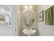 A stylish powder room with a pedestal sink, oval mirror, and decorative art at 11240 Windsor Place Circle Cir, Tampa, FL 33626