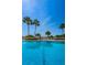 Sparkling community pool with palm trees overlooking the ocean and bright blue sky at 1270 Gulf Blvd # 506, Clearwater Beach, FL 33767