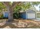 Landscaped front of the home with a mature shade tree and blue exterior paint at 1721 Sutton Pl, Dunedin, FL 34698