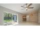 Open living room with tile flooring, ceiling fan, sliding glass doors, and view to kitchen at 1721 Sutton Pl, Dunedin, FL 34698