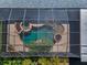 An aerial view showcases a uniquely designed swimming pool and patio within a screened enclosure, highlighting a modern outdoor space at 19719 Prince Benjamin Dr, Lutz, FL 33549