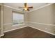 Spacious bedroom features a ceiling fan, large window, and beautiful dark-stained hardwood flooring at 19719 Prince Benjamin Dr, Lutz, FL 33549