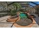 The screened-in pool and spa area features a rock waterfall, lush landscaping, and a surrounding brick patio at 19719 Prince Benjamin Dr, Lutz, FL 33549