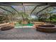 A screened-in pool area featuring a freeform pool, rock accents, and a spa, all surrounded by brick pavers at 19719 Prince Benjamin Dr, Lutz, FL 33549