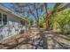 View of the home's side yard, featuring mature trees and the exterior wall with an AC unit at 2340 Kingston S St, St Petersburg, FL 33711
