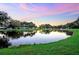 Scenic view of a tranquil pond reflecting a colorful sky with trees lining the water's edge at 37235 Cora Ave, Zephyrhills, FL 33542
