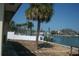 Scenic backyard view featuring a waterfront with a white fence and tropical palm trees at 390 Belle Point Dr, St Pete Beach, FL 33706
