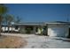 Charming single-story home with a light-colored exterior, garage, and a driveway, surrounded by lush greenery at 390 Belle Point Dr, St Pete Beach, FL 33706