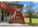 Elevated home with red staircases and a covered area underneath, surrounded by lush landscaping at 4508 Spring Rd, Valrico, FL 33596