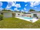 Lush green backyard with a kidney-shaped pool, white patio and house, manicured lawn, under a blue sky with puffy white clouds at 5314 13Th S Ave, Gulfport, FL 33707