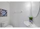 White half bathroom with pedestal sink, oval mirror, and blue flower art at 5728 Skytop Dr, Lithia, FL 33547