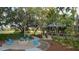 A stone fire pit with Adirondack chairs surrounded by landscaping and mature trees at 5728 Skytop Dr, Lithia, FL 33547