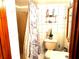 Bathroom showcasing a toilet, shower, mirror, and storage shelves with toiletries at 6305 W Hanna Ave, Tampa, FL 33634