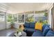 Inviting screened porch with cozy blue sofa, stylish tile flooring, and serene backyard view for relaxed outdoor living at 7716 W Hiawatha St, Tampa, FL 33615