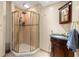 Bathroom featuring a corner shower with gold trim, elegant vanity, and a towel at 8329 Broken Willow Ln, Port Richey, FL 34668