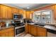 Kitchen featuring wood cabinets, stainless steel appliances, double sink, and a window overlooking the lanai at 8329 Broken Willow Ln, Port Richey, FL 34668
