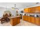 Kitchen offers wood cabinets, island with seating, tile floors, and view into the dining room at 8329 Broken Willow Ln, Port Richey, FL 34668
