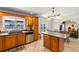 Kitchen features island, tile floors, wood cabinets, stainless steel dishwasher and view into dining room at 8329 Broken Willow Ln, Port Richey, FL 34668
