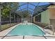 Sparkling in-ground pool within a screened enclosure with a safety ladder for enjoying swimming year-round at 8329 Broken Willow Ln, Port Richey, FL 34668