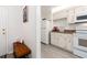 Efficient kitchen featuring white appliances, cabinets, countertop, and a cozy entry bench with a pillow at 100 Bluff View Dr # 317A, Belleair Bluffs, FL 33770
