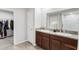Bathroom with double sinks, granite countertop, wood cabinets, and access to shower and walk-in closet at 10105 Paradise Fish Dr, Riverview, FL 33578