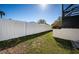 Fenced backyard with lush green grass and partial view of a screened enclosure in the background at 1017 Jamaica Way, Tarpon Springs, FL 34689