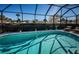 Stunning pool within a screened enclosure, complemented by mature landscaping and comfortable lounge area at 1017 Jamaica Way, Tarpon Springs, FL 34689