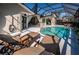 A sun-soaked pool area featuring a sparkling pool, lounge chairs, and seamless indoor-outdoor living at 1017 Jamaica Way, Tarpon Springs, FL 34689