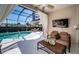 Relaxing screened patio area with a sparkling pool, cozy lounge chairs, and outdoor TV at 1017 Jamaica Way, Tarpon Springs, FL 34689