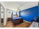 Bedroom features hardwood floors, ceiling fan, a large bed, and an accent blue painted wall at 1021 Augusta Dr, Sun City Center, FL 33573