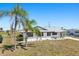 Well-kept single-story home showcases a white exterior with black trim, complemented by mature palm trees at 1021 Augusta Dr, Sun City Center, FL 33573