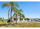 Charming single-story home featuring a well-maintained lawn, palm trees, and a bright exterior with black window trim at 1021 Augusta Dr, Sun City Center, FL 33573